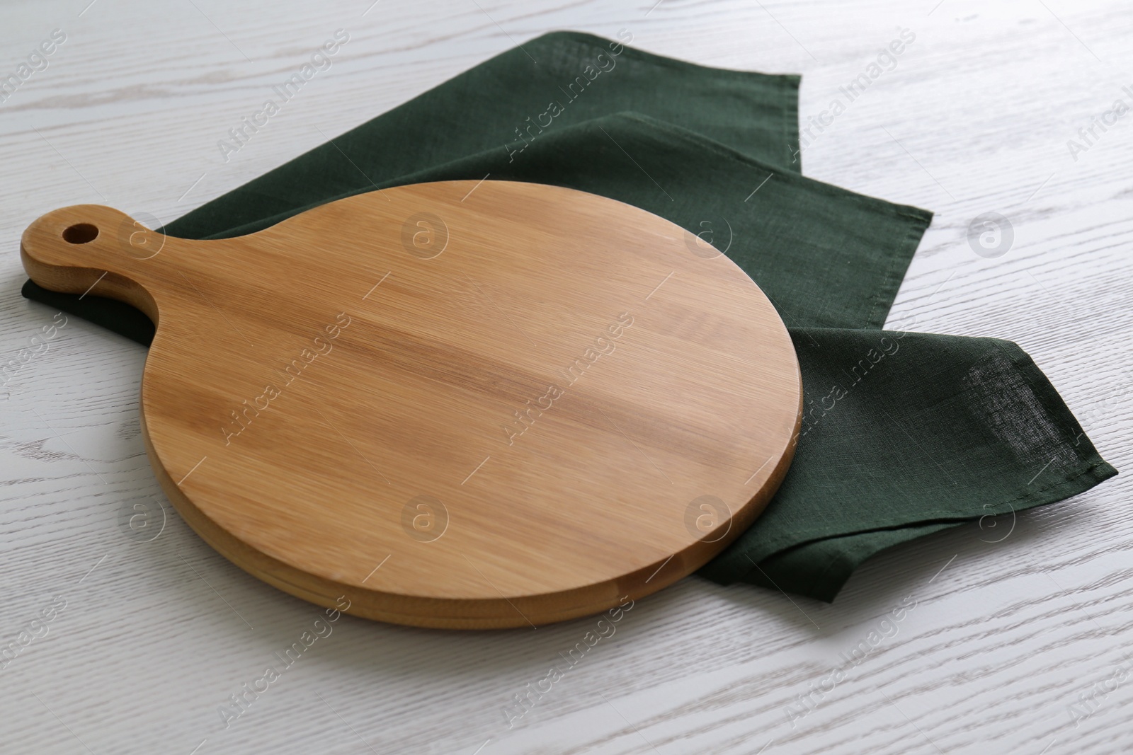 Photo of Empty wooden board and green napkin on white table