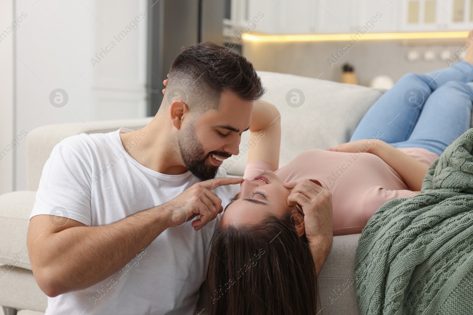Photo of Affectionate young couple spending time together on sofa indoors