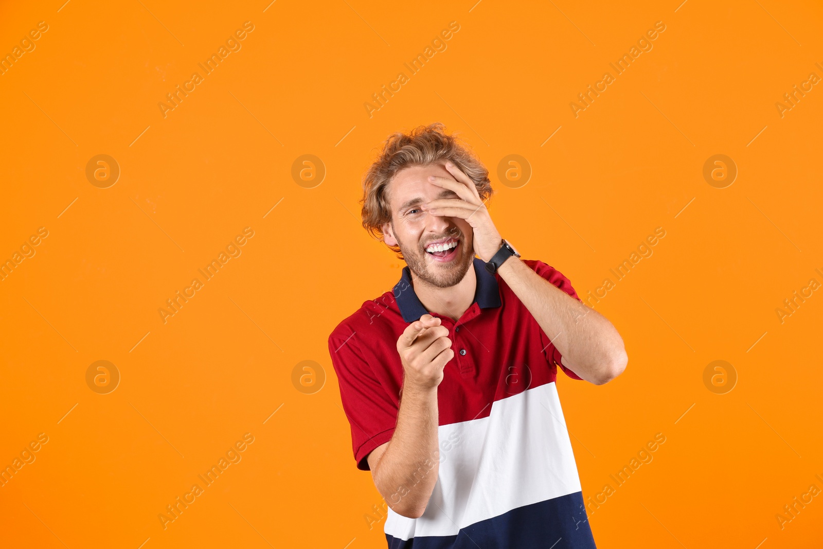 Photo of Handsome young man laughing on color background