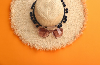 Photo of Stylish summer hat and sunglasses on color background, top view
