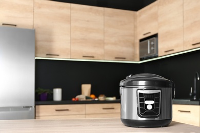 Photo of Modern multi cooker on table in kitchen. Space for text