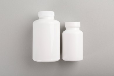 Photo of Blank white pill bottles on light grey background, top view