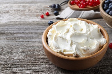 Photo of Tasty cream cheese and fresh berries on wooden table. Space for text