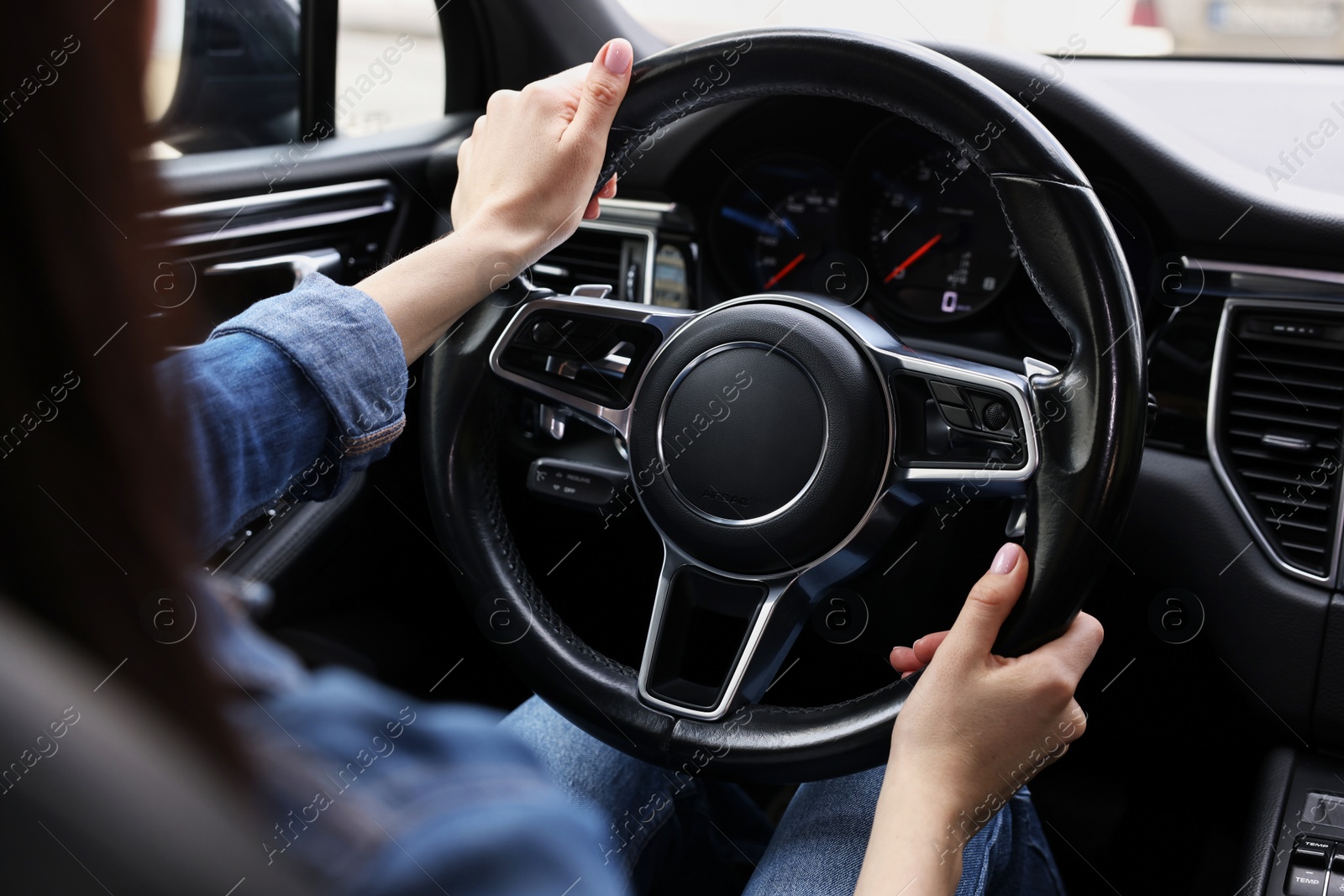 Photo of Woman holding steering wheel while driving her car, closeup