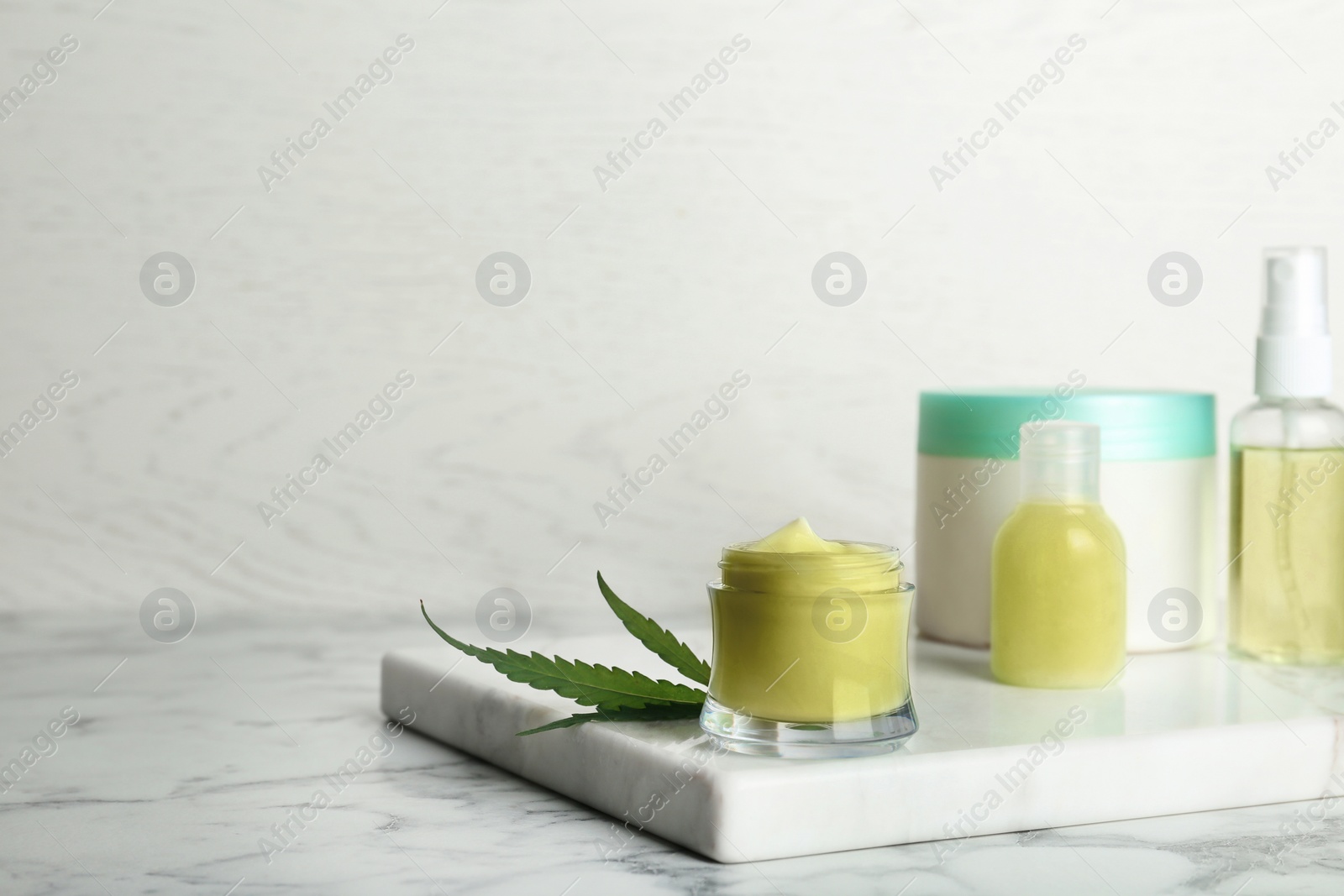 Photo of Composition with hemp lotion on marble table. Space for text