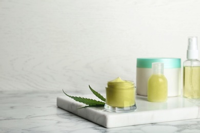 Photo of Composition with hemp lotion on marble table. Space for text