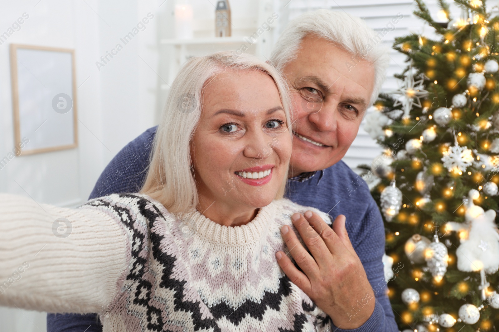 Photo of Happy mature couple taking selfie at home. Christmas celebration