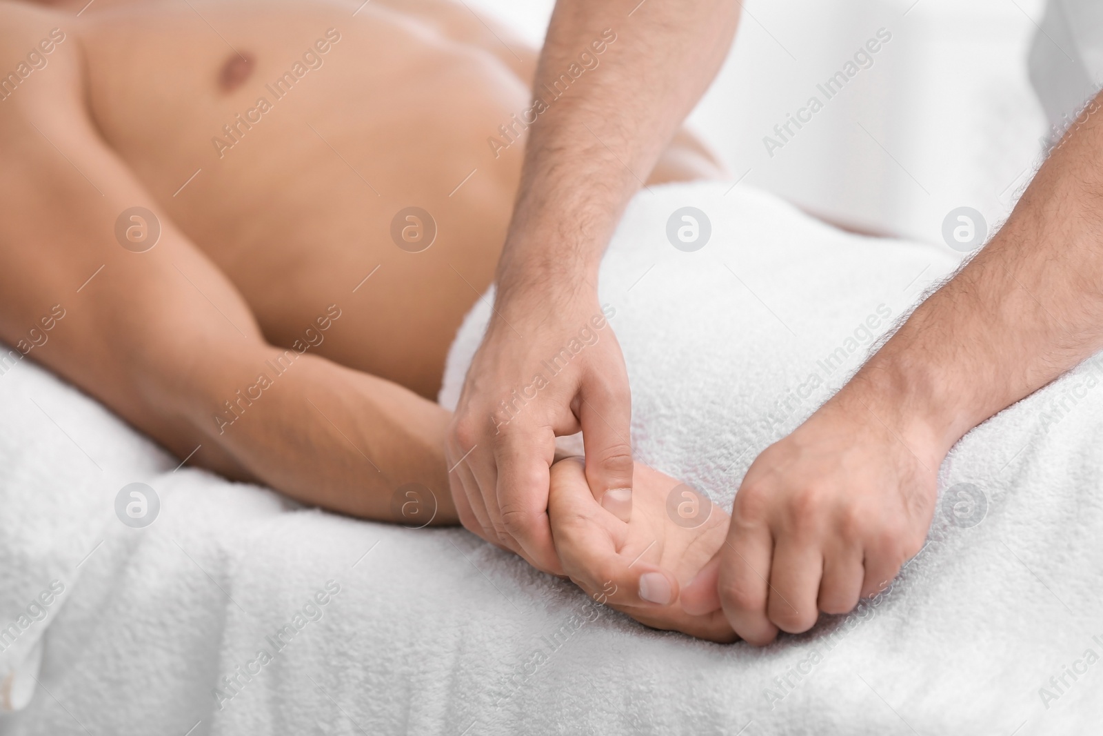 Photo of Young man receiving massage in salon, closeup