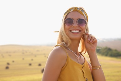 Beautiful happy hippie woman with spikelet in field, space for text