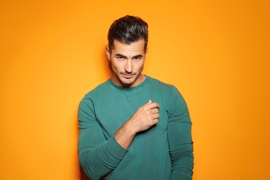 Young man with trendy hairstyle posing on color background