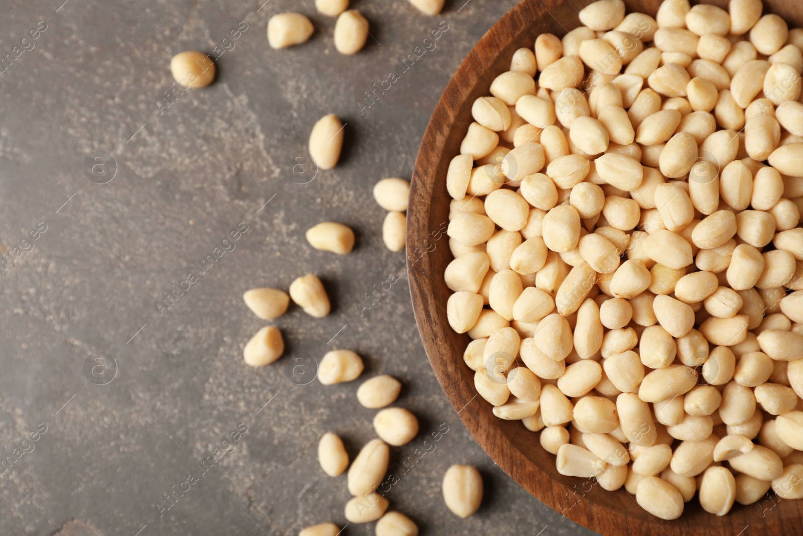 Photo of Shelled peanuts in bowl and space for text on table, top view