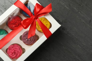Box with different cupcakes on dark background, top view