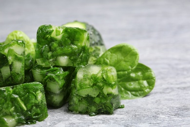 Photo of Ice cubes with cucumber slices and herbs on grey table, closeup