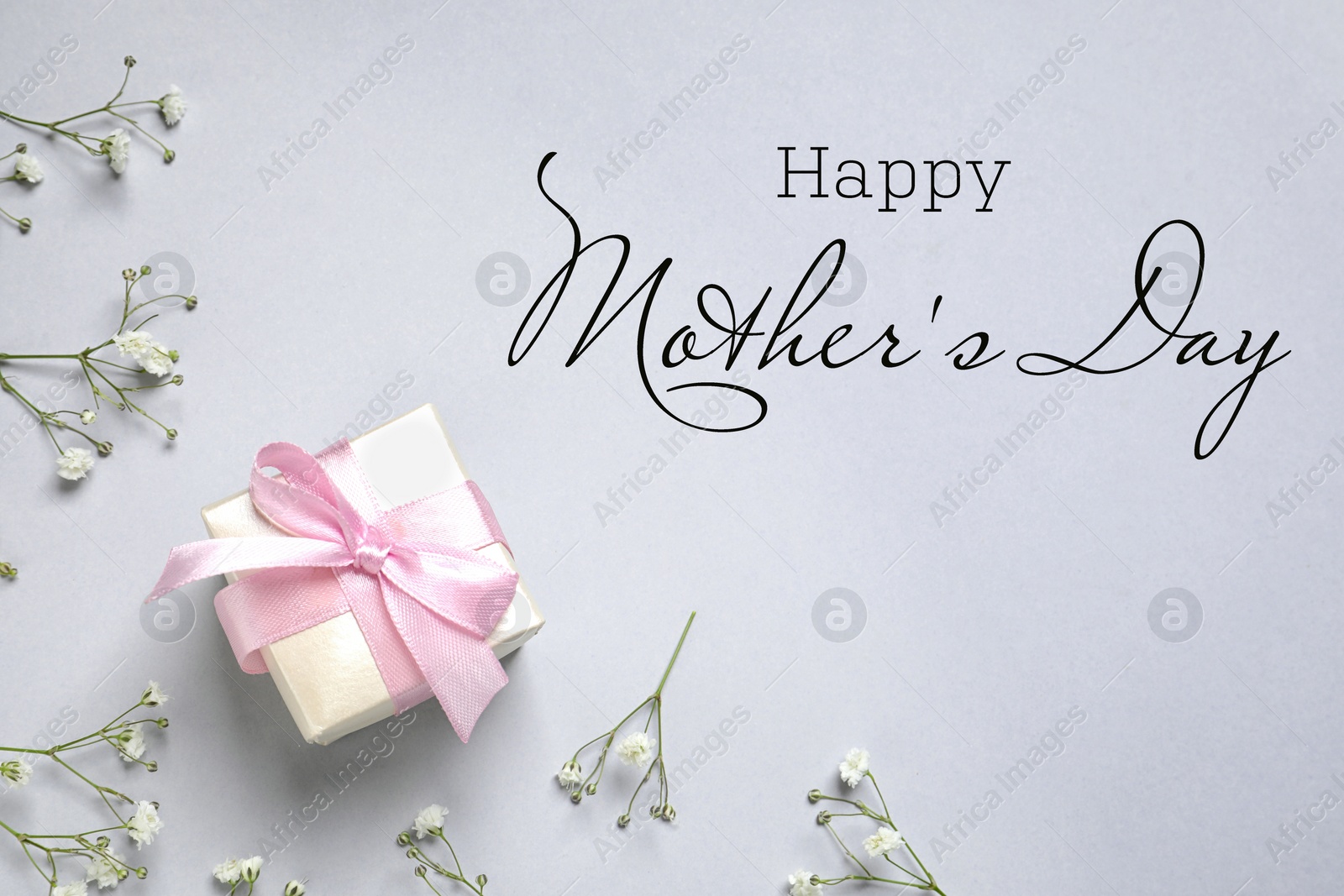 Image of Happy Mother's Day. Greeting card with gift box and beautiful flowers on light grey background, flat lay