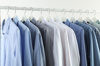 Photo of Men's clothes hanging on wardrobe rack against white background