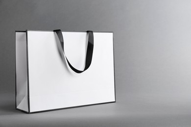 Photo of One paper bag on grey background, space for text. Mockup for design