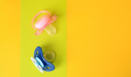 Baby pacifiers on color background, flat lay. Space for text