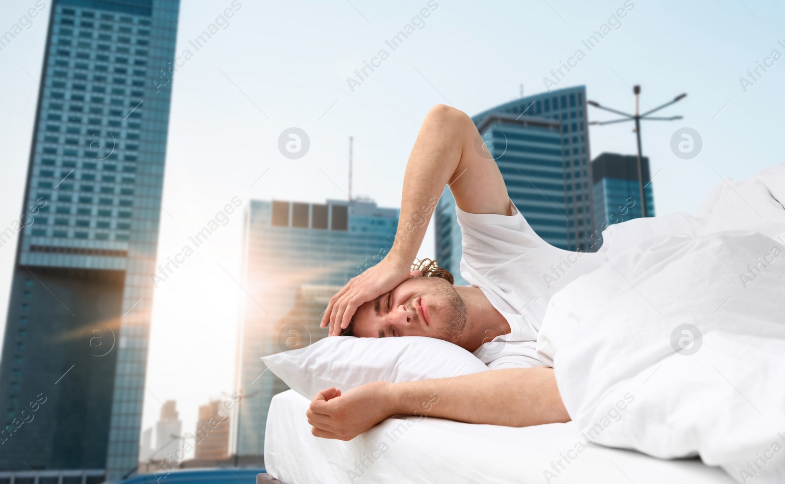 Image of Man in bed and beautiful view of cityscape on background. Poor sleep because of urban noise