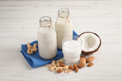 Different nut milks on white wooden table