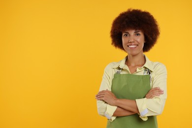 Photo of Portrait of happy young woman in apron on orange background. Space for text
