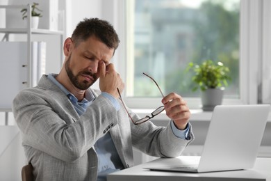 Photo of Man suffering from eyestrain at desk in office