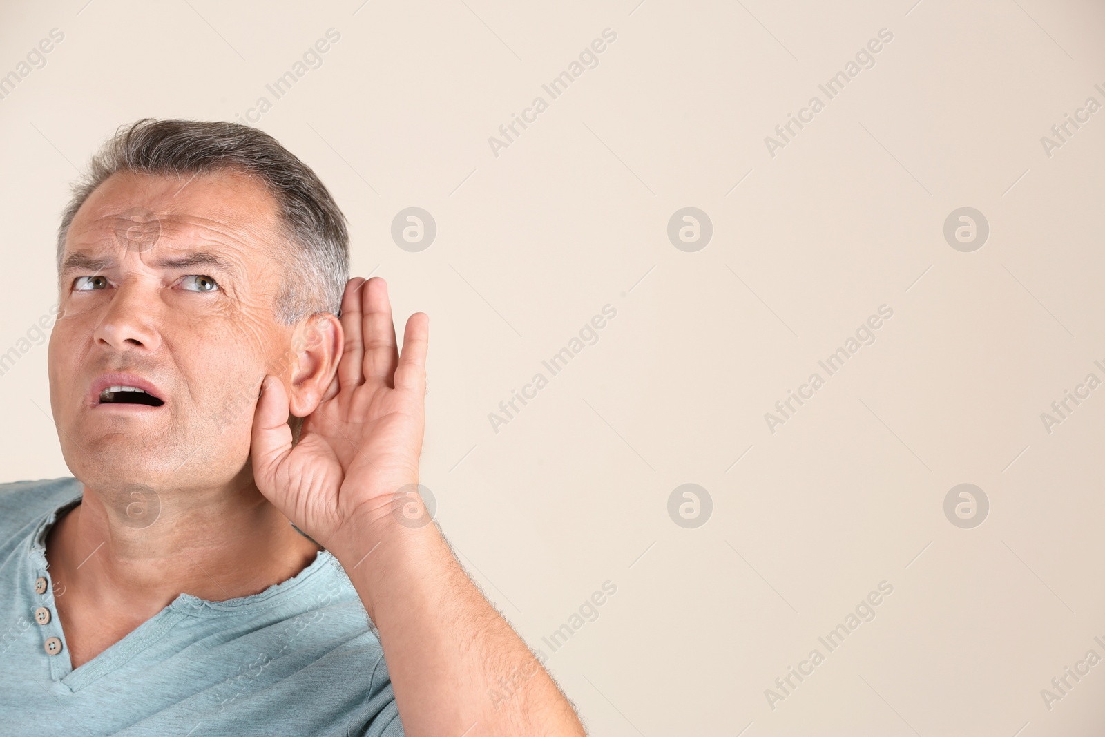 Photo of Mature man with hearing problem on light background. Space for text