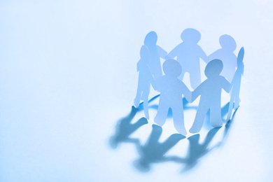Paper people chain making circle on light blue background, space for text. Unity concept