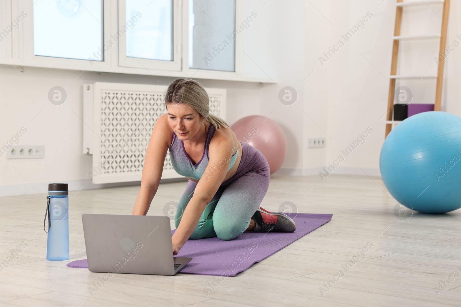 Photo of Online fitness trainer. Woman watching tutorial on laptop at home