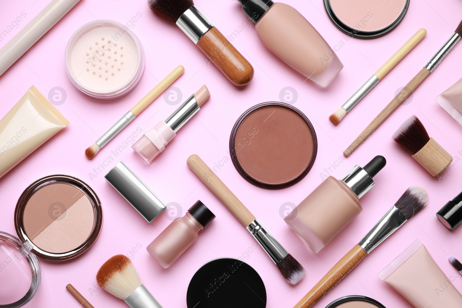 Photo of Face powders and other decorative cosmetic products on pink background, flat lay