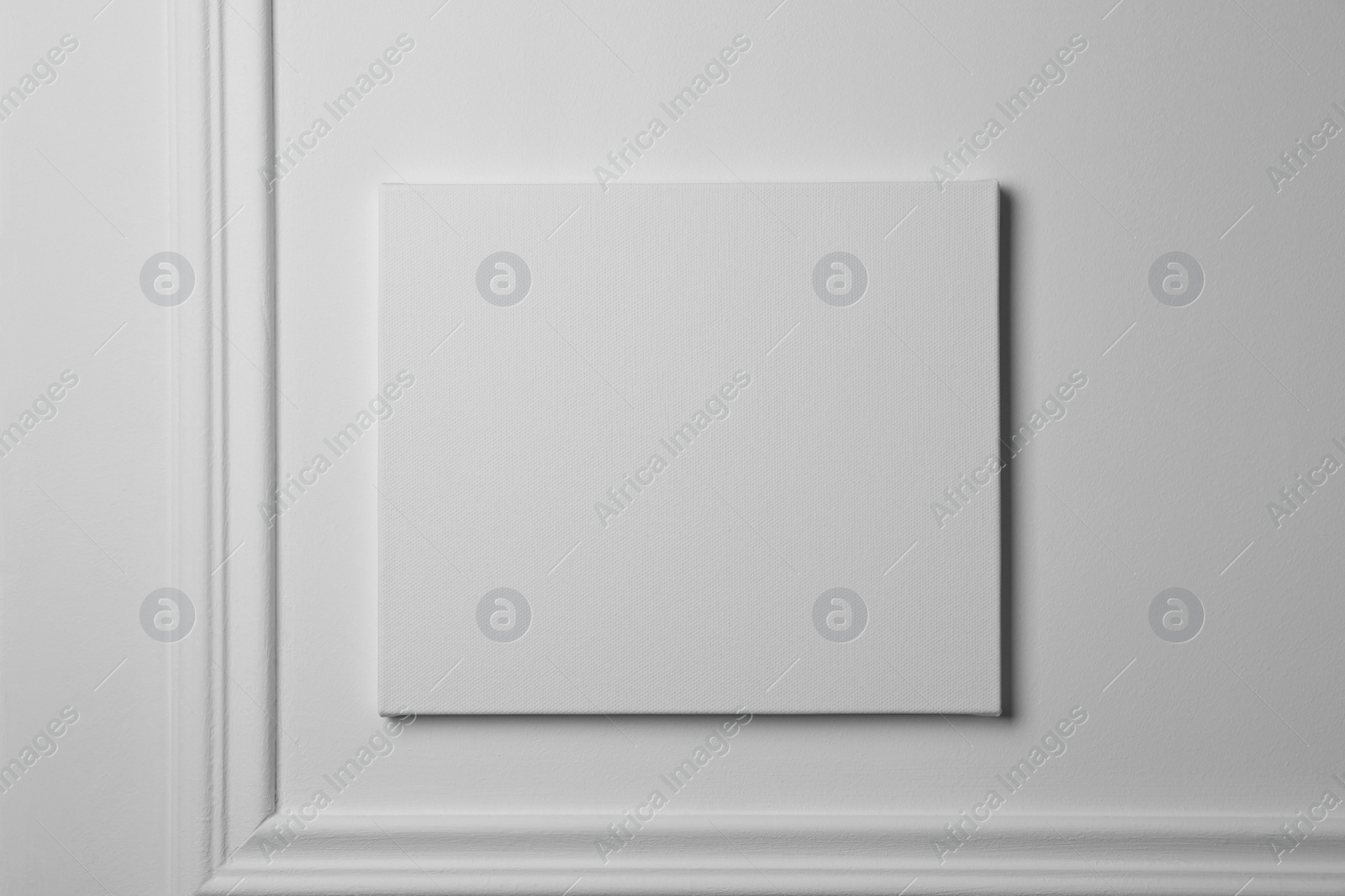 Photo of Blank canvas hanging on white wall, space for text