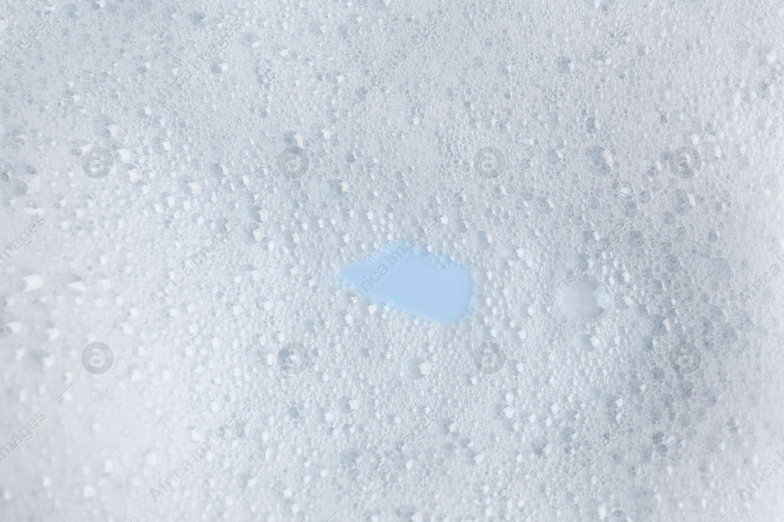 Photo of White fluffy foam on light blue background, top view