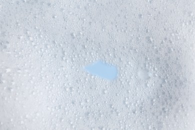 Photo of White fluffy foam on light blue background, top view