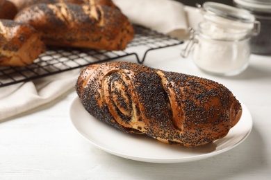 Photo of Plate with freshly baked poppy seed roll on table