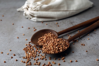 Photo of Spoons with uncooked buckwheat on table. Organic wholesome product