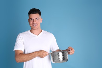 Happy man with pot on light blue background, space for text