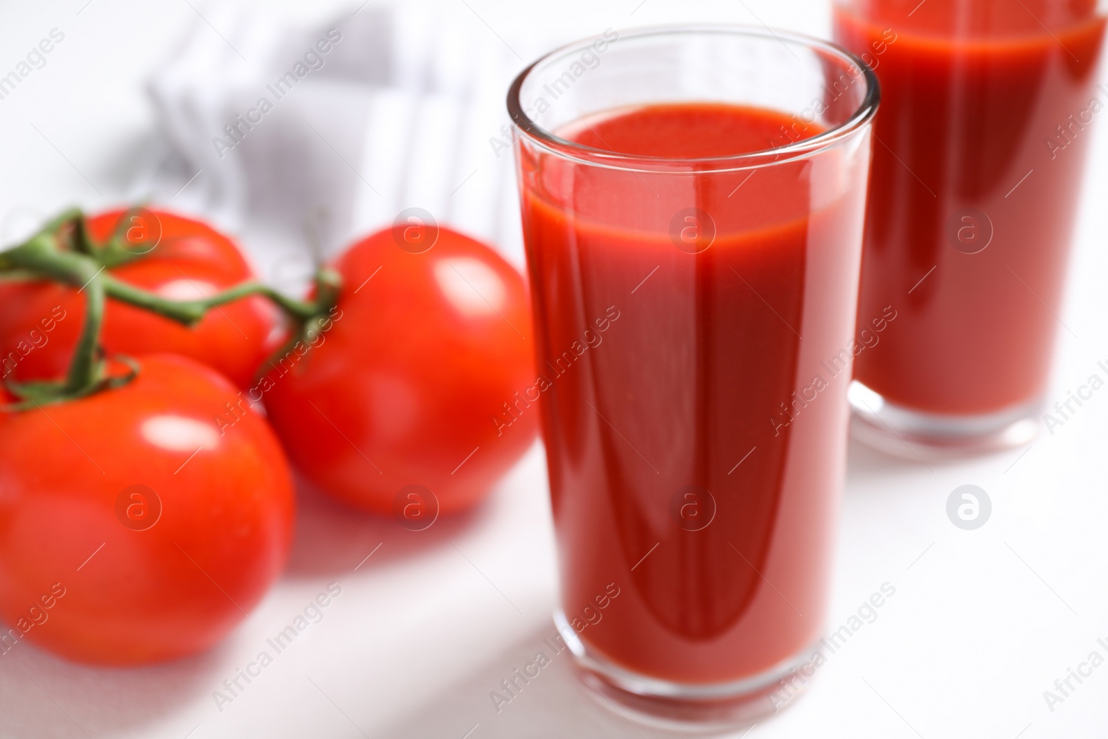 Photo of Delicious fresh tomato juice on white table, closeup