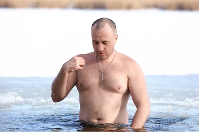 Photo of MYKOLAIV, UKRAINE - JANUARY 19, 2021: Man immersing in icy water on winter day. Traditional Baptism ritual