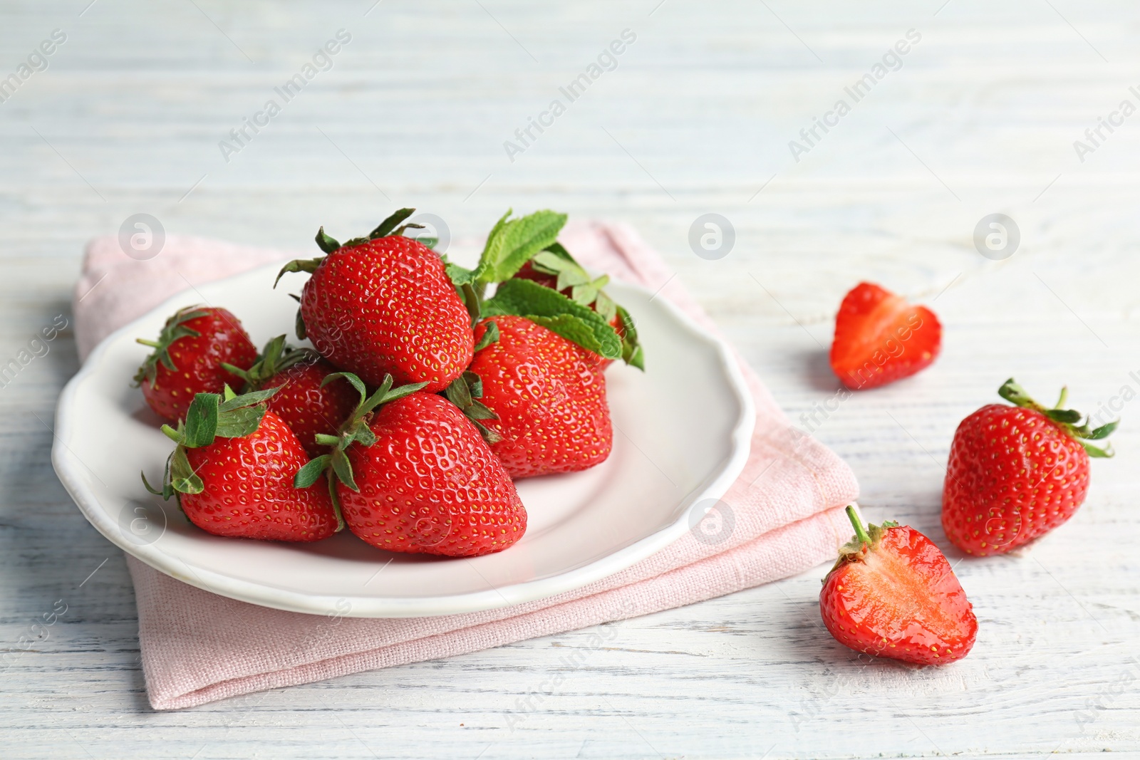 Photo of Plate with ripe red strawberries and mint on table