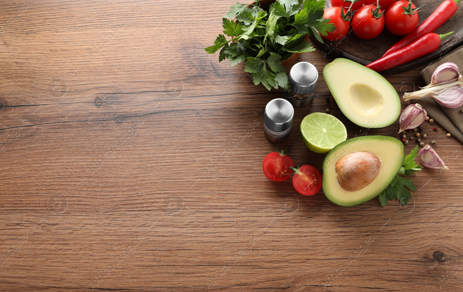 Photo of Fresh guacamole ingredients on wooden table, flat lay. Space for text