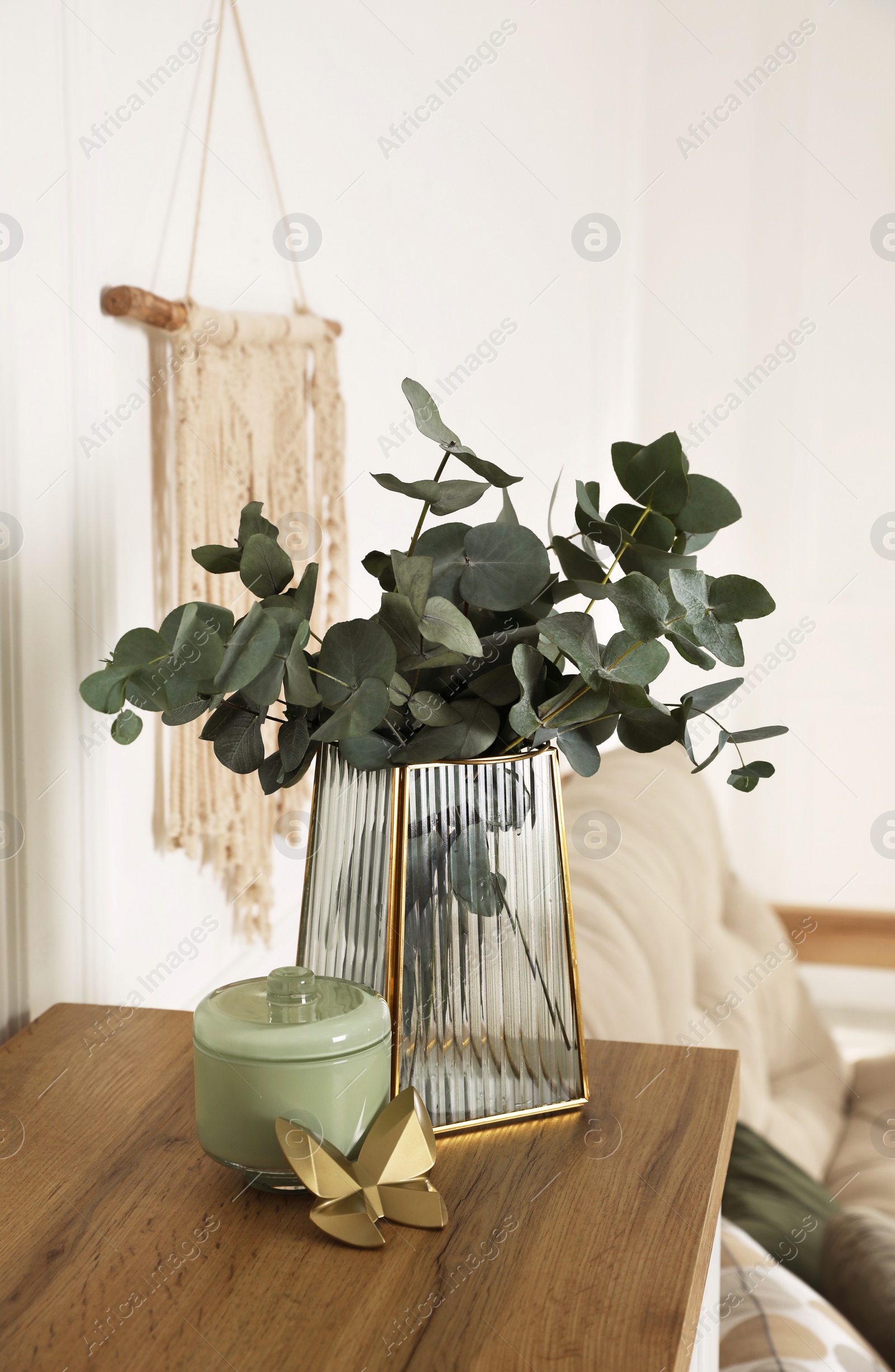 Photo of Stylish glass vase with eucalyptus branches and beautiful decor elements on wooden table indoors