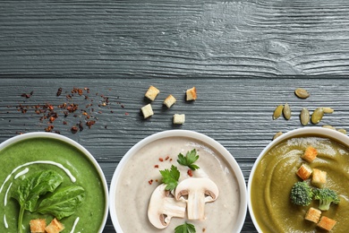 Photo of Various cream soups and space for text on wooden background, flat lay. Healthy food