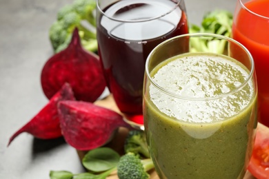 Photo of Delicious vegetable juices and fresh ingredients on grey table, closeup