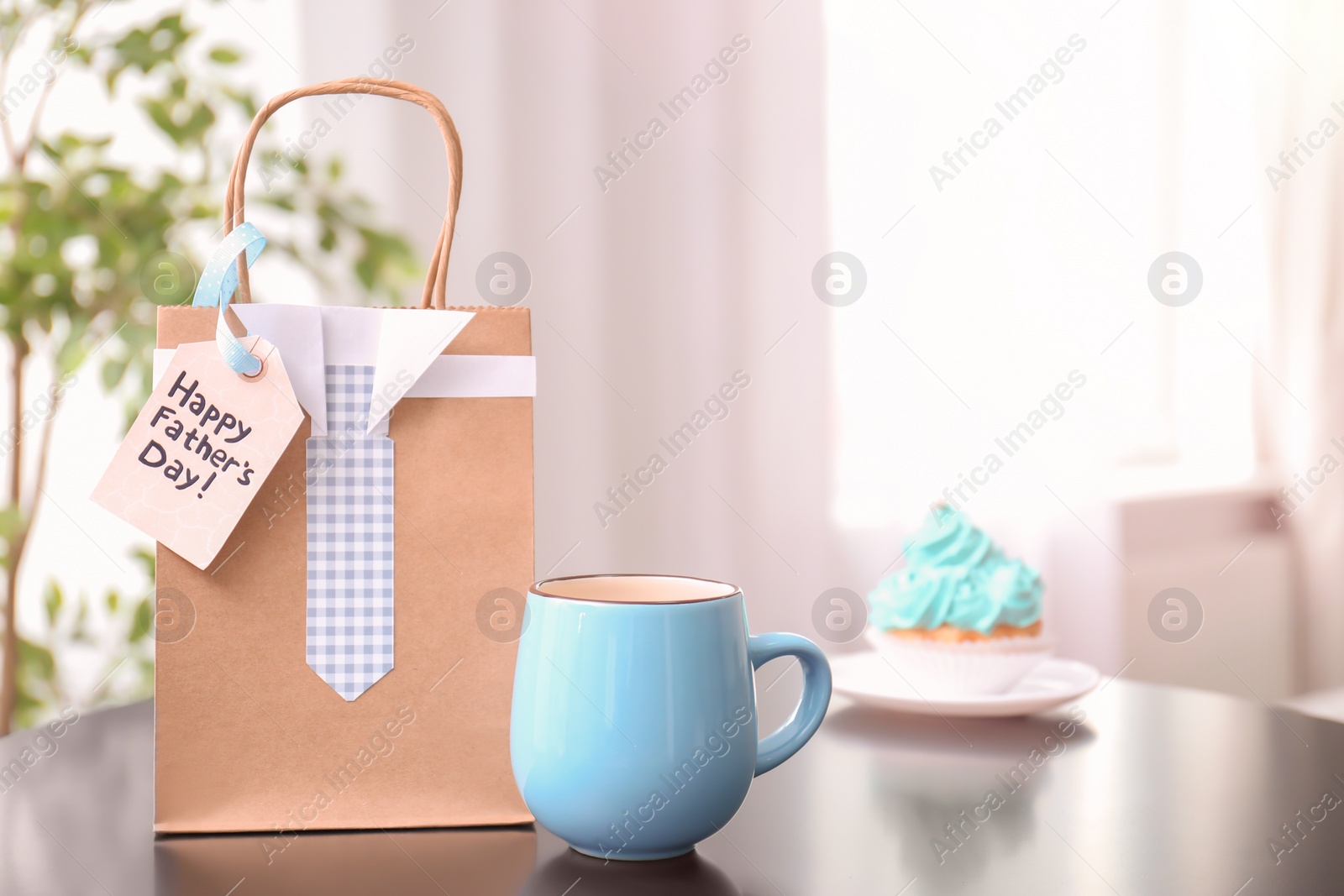 Photo of Cup and gift bag on table. Father's day celebration