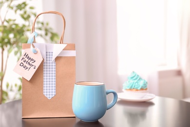 Cup and gift bag on table. Father's day celebration