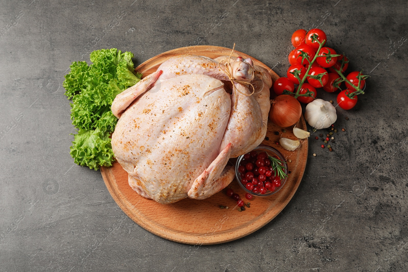Photo of Wooden board with raw spiced turkey and ingredients on grey background, top view