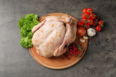 Photo of Wooden board with raw spiced turkey and ingredients on grey background, top view