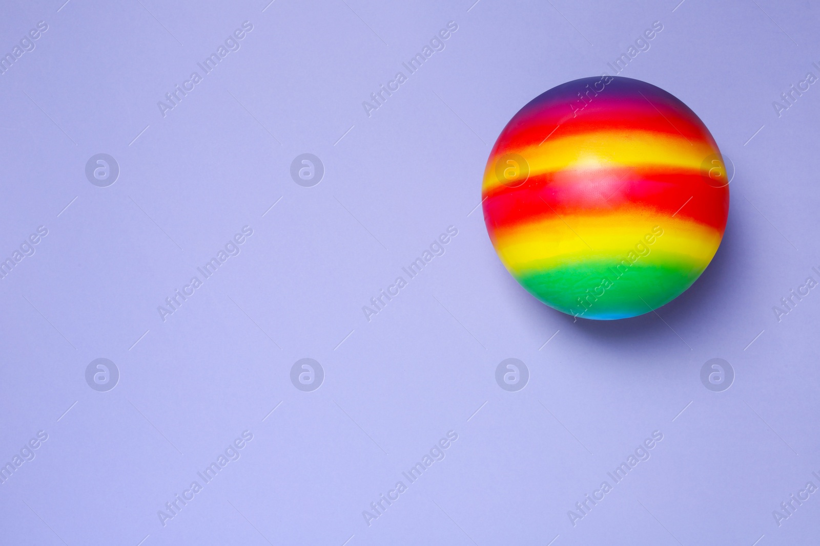 Photo of New bright kids' ball on lilac background, top view. Space for text