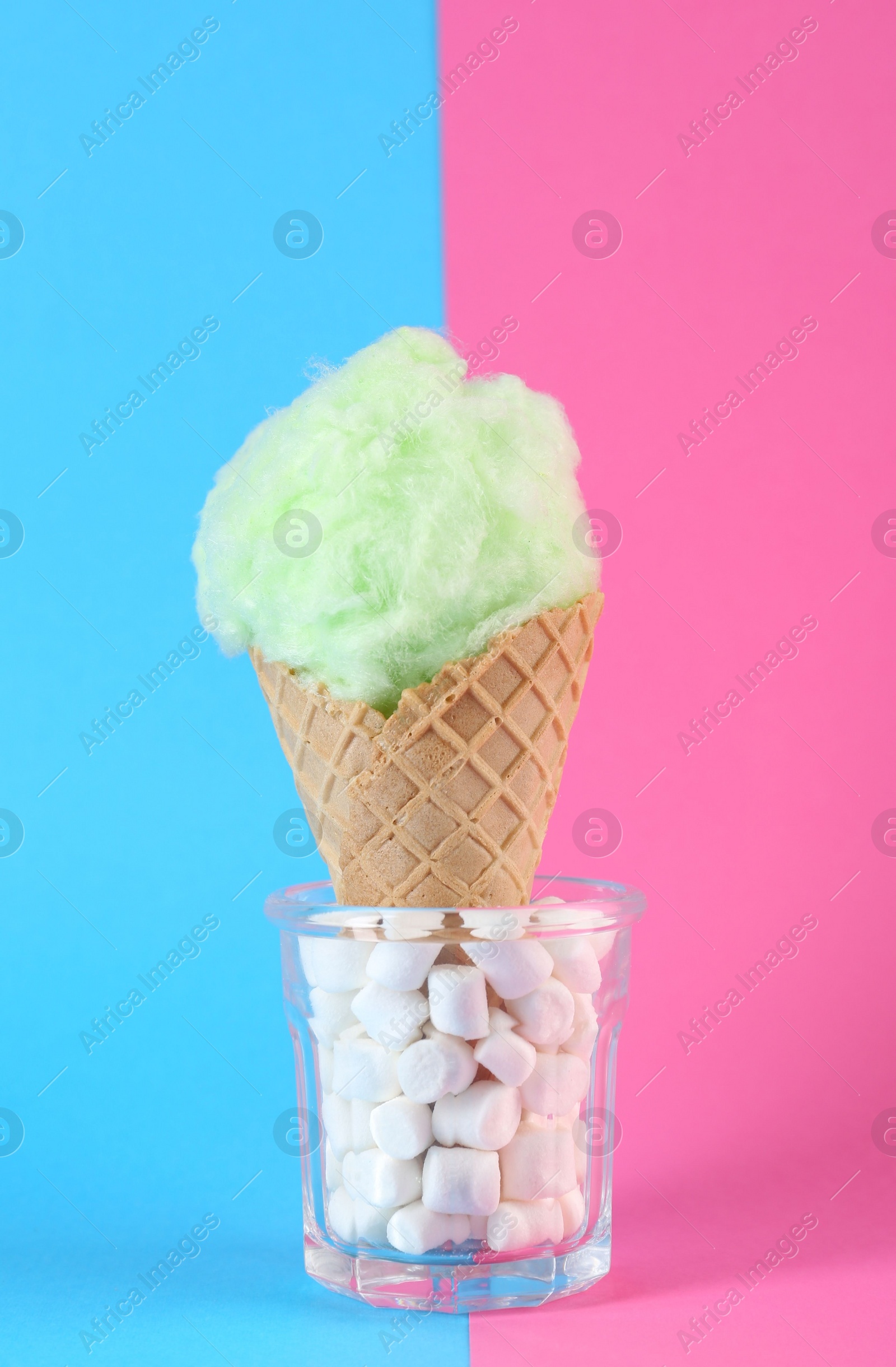 Photo of Sweet cotton candy in waffle cone on color background