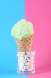 Photo of Sweet cotton candy in waffle cone on color background