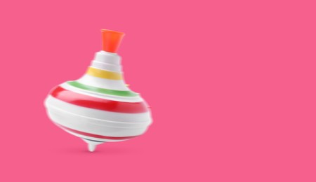 One spinning top in motion on pink background, banner design with space for text. Toy whirligig
